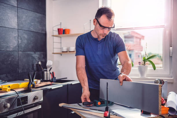 Man working on kitchen cabinet refacing at home.