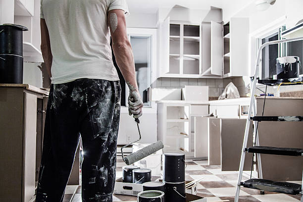 Worker with painting equipment on the kitchen area.