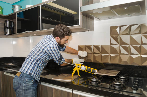 Man working on the installation of the new kitchen backsplash at home.