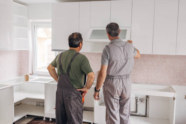 Workers working on cabinet refacing in the kitchen area.