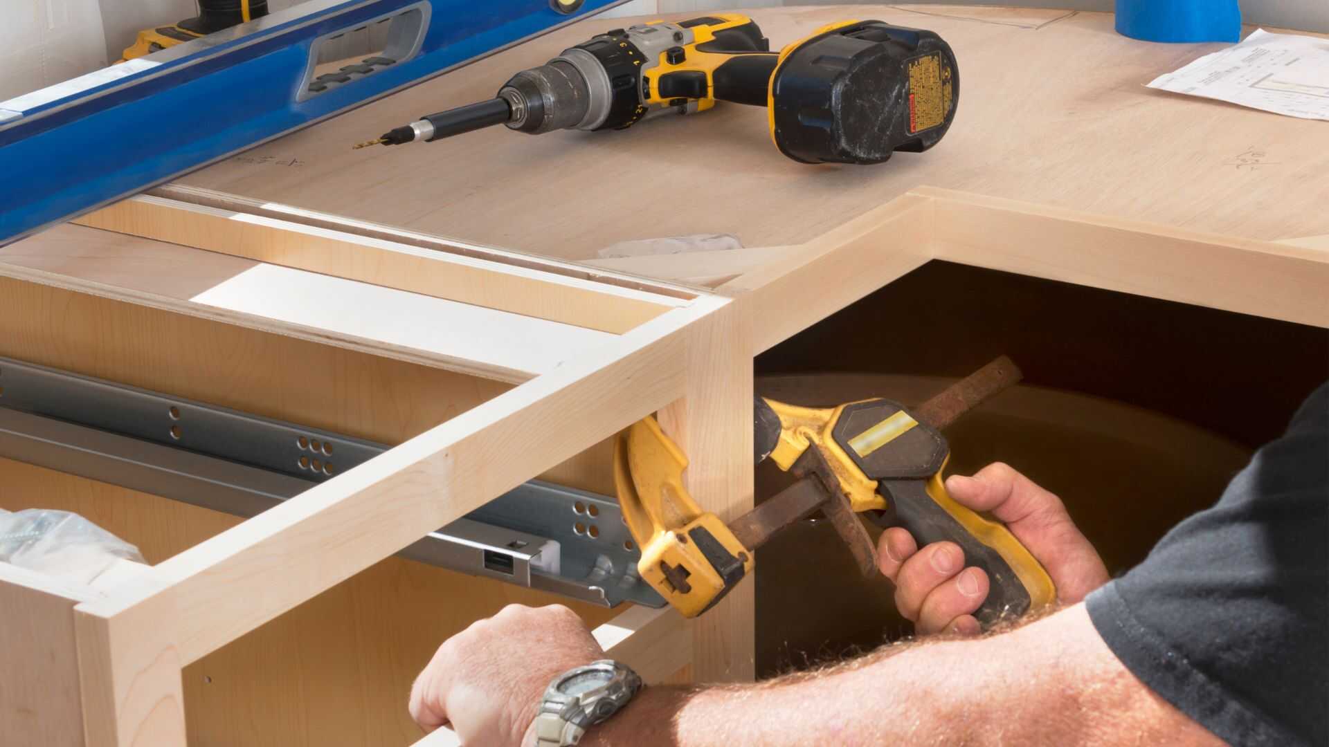 Construction worker installing kitchen cabinets